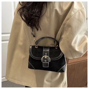 Close-up of black suede and leather patchwork crossbody bag with gold buckle detail