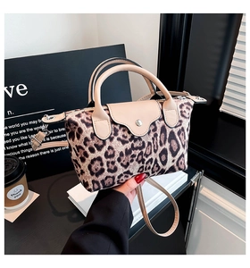 Detail of leopard print handbag with beige leather trim and silver snap closure