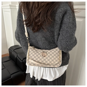 Detail of beige crescent shoulder bag with golden M hardware and textured letter print