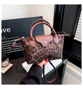 Detail view of the leopard print handbag showing nylon texture and brown leather trim