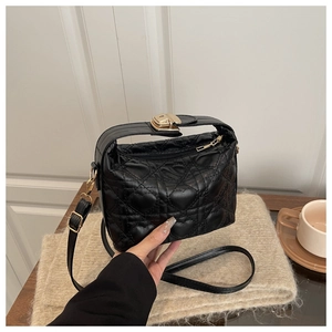 Close-up of black quilted heart pattern PU leather bag with premium gold metal lock detail