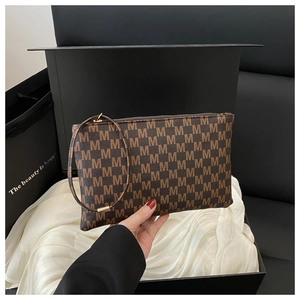 Close-up of brown monogram clutch bag with M pattern next to premium black gift box