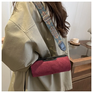 Detail view of burgundy cylinder bag with bohemian floral strap and suede texture
