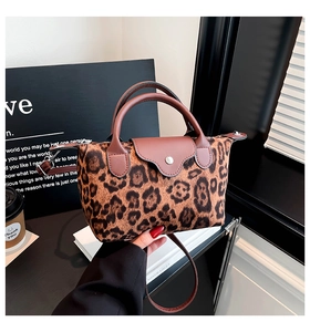 Detail of leopard print crossbody bag with brown leather handles and silver snap buckle
