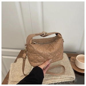 Detail of khaki heart-quilted PU leather bag with gold hardware in cozy setting