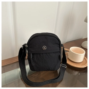 Close-up of black nylon crossbody bag with M FASHION metal logo and adjustable strap
