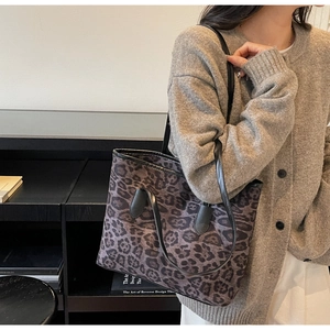 Detail of large leopard print tote bag with black leather straps on model's shoulder