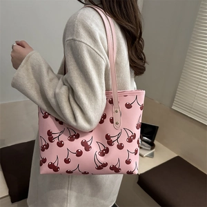 Grand sac fourre-tout rose avec imprimé cerises porté par un mannequin en manteau chic