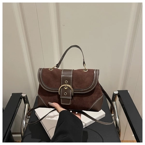 Detail of dark brown suede crossbody bag with gold buckle and contrast stitching