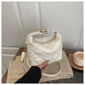 Detail of white quilted heart handbag with gold twist lock and smooth leather strap