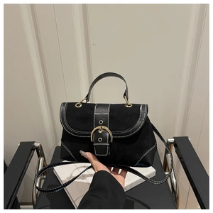 Detail of black vintage suede crossbody bag featuring a large gold horseshoe buckle
