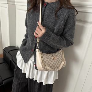 Beige monogram shoulder bag with gold chain and M logo worn by model on grey sweater