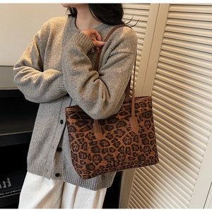 Detail of leopard print tote bag with brown leather handles worn over a shoulder