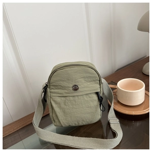 Detailed shot of olive green nylon bag texture and round M metal logo with woven strap