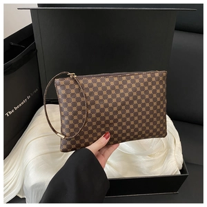 Close-up of a vintage brown geometric pattern clutch with a practical wrist strap detail