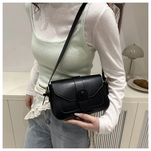 Minimalist black leather square crossbody bag worn by a model in a modern home setting