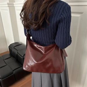 Sac fourre-tout classique bordeaux en cuir avec large bandoulière porté par un mannequin