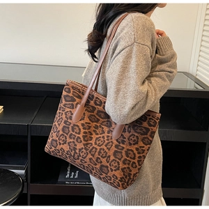 Detail shot of a large leopard print tote bag with brown straps worn on a woman's shoulder