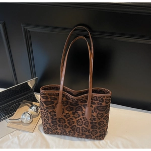 Detailed view of leopard print tote bag with brown straps in a lifestyle setting