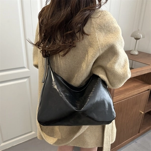 Grand sac fourre-tout noir brillant avec large bandoulière porté par un mannequin