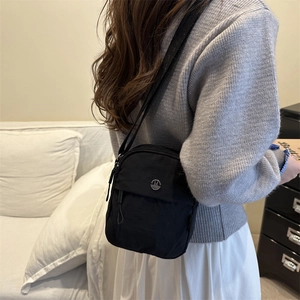 Chic black mini crossbody bag with metal M buckle shown in a lifestyle side view