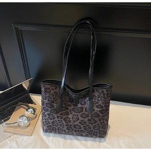 Detail of leopard print tote bag with black handles in a modern office desk setting