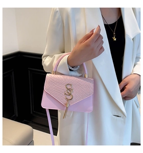 Détail du sac rose à texture tissée avec logo SS doré et gland porté par un mannequin