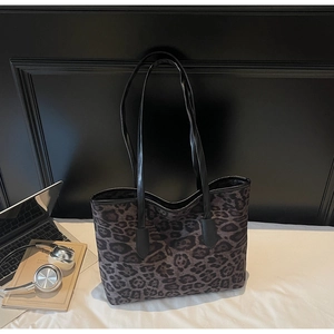 Detail of leopard print tote bag with black leather handles and laptop in office setting