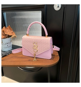 Détail du sac en similicuir rose avec rabat à motif pierre, logo SS doré et pompon chic