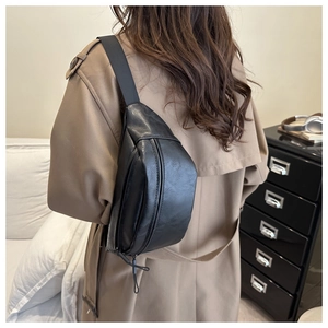 Vue arrière d'un sac bandoulière noir texture litchi porté sur un trench-coat kaki