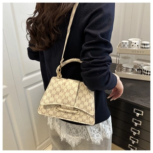 Detail van een beige monogram crossbodytas gedragen door een model in een interieur