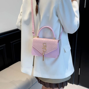 Sac bandoulière rose motif crocodile avec logo doré et gland sur blazer blanc