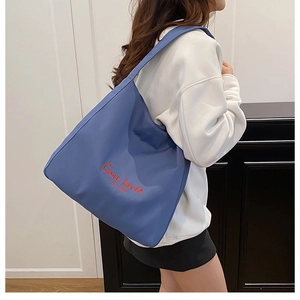 Detail of navy blue tote bag with red 'C'est lavie' embroidery on nylon fabric