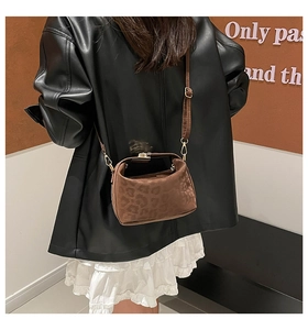 Close-up of brown leopard print crossbody bag with gold buckle on a stylish model