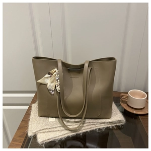 Détail du sac cabas en similicuir kaki avec un foulard en soie et logo embossé élégant