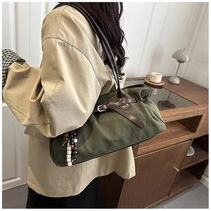 Detail of dark green canvas tote bag with leather strap and tassel in vintage setting