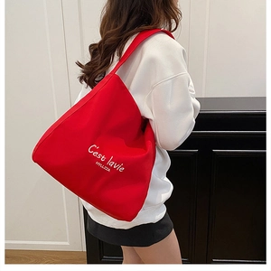 Red canvas tote bag with white C'est la vie print shown in a spacious lifestyle view