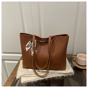 Détail d'un sac cabas en cuir marron avec fermoir métallique et foulard en soie décoratif