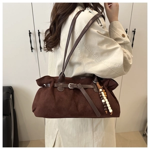 Close-up of brown suede tote bag with decorative wooden beads and buckle detail