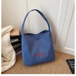 Detail of navy blue tote bag featuring red C'est la vie embroidery on nylon fabric