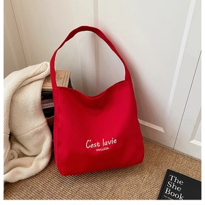Detail of red canvas tote bag with white typography displayed in a cozy lifestyle setting