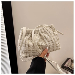Detail einer weißen Tweed-Beuteltasche mit Kordelzug und schmalem Leder-Schultergurt