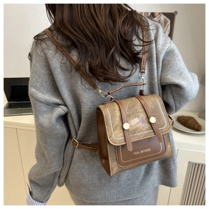 Close-up of retro brown backpack with Tidal Dryness cat print and metal buckle detail