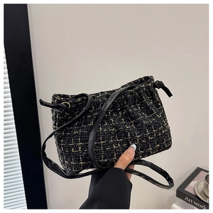 Detail der schwarz-goldenen Tweed-Beuteltasche mit Kordelzug und schmalem Lederriemen