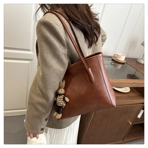 Brown leather tote bag with long shoulder straps and a cute houndstooth bunny charm