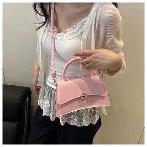 Detail of pink crossbody bag with gold twist lock and handle shown on a model