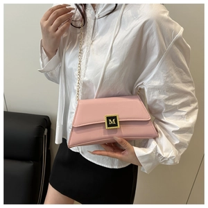 Detailed close-up of pink leather crossbody bag with golden M buckle on white shirt