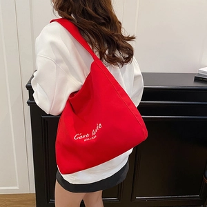 Chic red canvas tote bag with white C'est la vie text worn by model in a casual setting