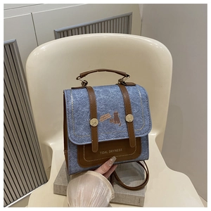 Detail of retro blue denim backpack with brown leather trim and cat print motif