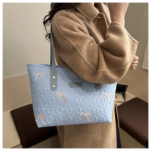 Detail of light blue tote bag with butterfly embroidery and quilted lattice texture